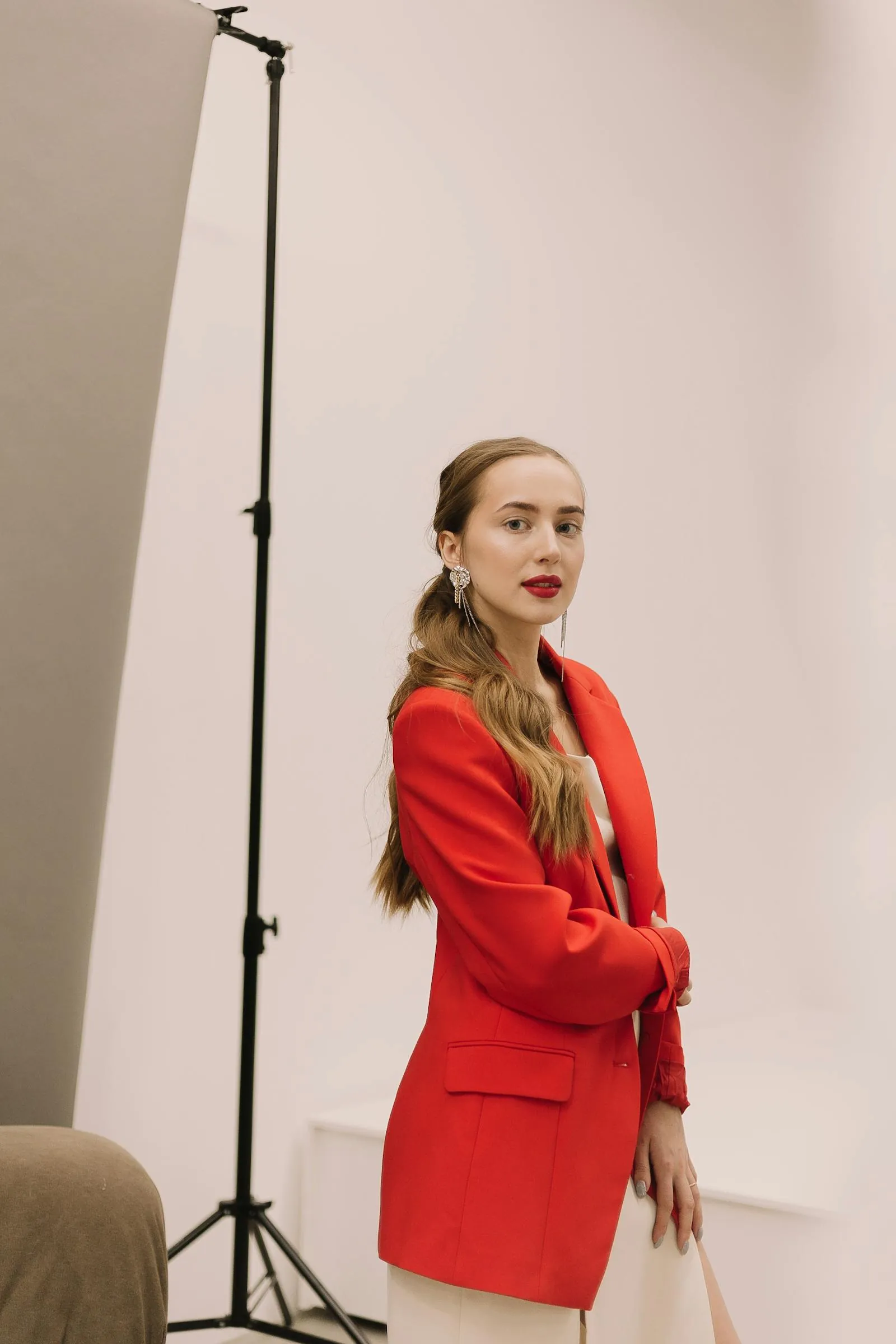 A model in profile wearing a layered linen coat, shot against a chalky stone wall in raking afternoon light — frame 12 of the Atrium SS25 sequence.